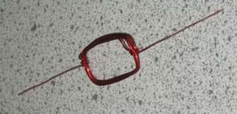 A photo shows red, magnet wire coiled into the shape of a rectangle. 