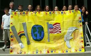 Photograph of 10 kids holding a large banner with the word HOPE spelled out with images of the twin towers, rainbow, globe, flag and dove.