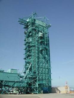 : Photograph of a very tall (~15-story) rocket launching tower, constructed of steel beams.