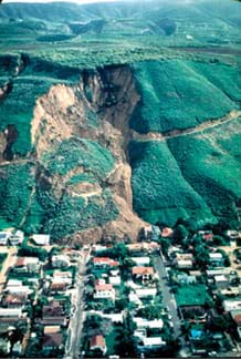 Aerial photo shows hillside and road that slid down into a neighborhood of houses.