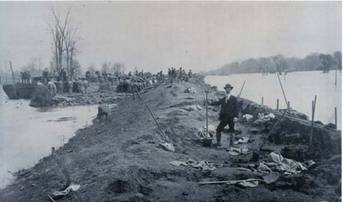 Black/white photo shows men with shovels on high ground, surrounded by water.