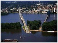A photograph shows two bridges, partially submerged by a surrounding high-water river.