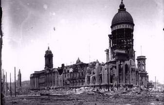 Photo shows a large building with many crumbled exterior walls, exposing the steel frame.