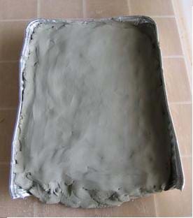 Photo shows entire bottom and most sides of silver rectangular pan filled with smoothed modeling clay.