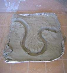 Photo shows a pan of clay with a meandering ditch cut into it.