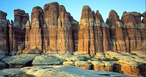 Photo of huge pointed rock spires with horizontal orange, white and brown stripes.