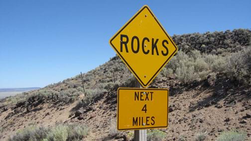 A yellow road sign: ROCKS - NEXT 4 MILES.