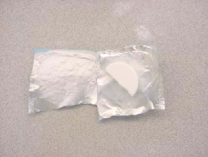 A photograph shows an antacid tablet broken into halves and placed on its open wrapper. The half on the left has been crushed into a powder.