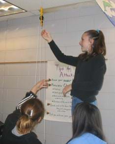 A photograph of a student attaching a pulley to the ceiling.