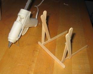 A photograph of the beginning construction of catapult (the base). Shown also is a hot glue gun. 
