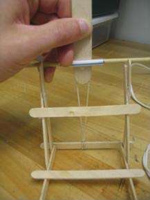 A photograph showing the stretching out of the rubber band and testing the rotation around wooden dowel.