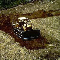 Photograph of a bulldozer pushing piles of soil. 