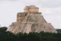 Photo shows a pyramid-shaped structure above the trees, with four intermediate ledges and a flat top.