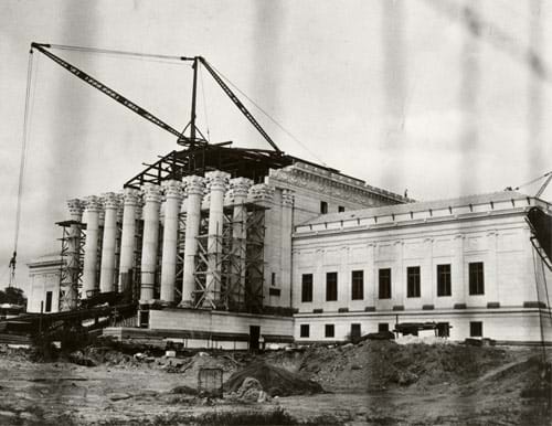 Photograph of a crane lifting materials onto a building under construction.
