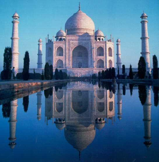 Photo of a white marble square building topped with a gently swelling dome in front of a long pool of water.