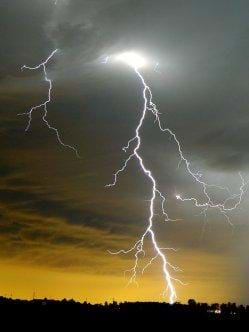 Photo shows a dark sky with a bright and jagged lightning bolt.