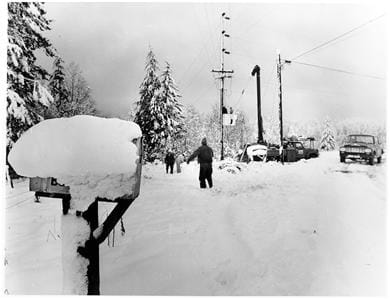 A black and white photo shows people out shoveling snow after a heavy snowstorm.