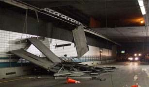 Photo inside a tunnel shows concrete panels dangling from the ceiling and piled on the ground on top of a crushed car. 