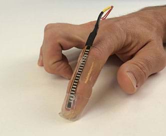 A photograph shows a person’s hand with a flex sensor taped onto its index finger. Additional wires have been soldered on the flex sensor.