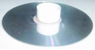 Fotografía de un CD con el tapón de una botella pegado en el centro de un CD.