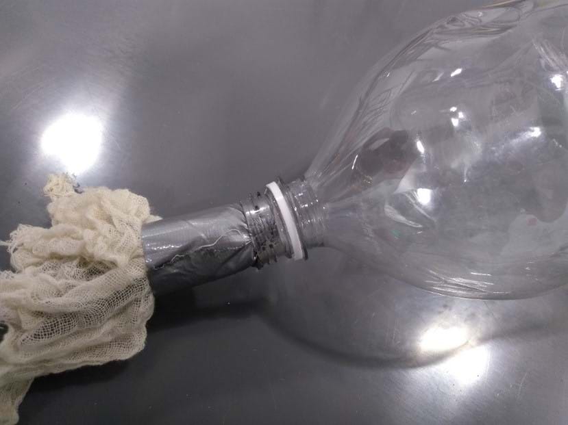 The second of three pictures showing possible steps that students may do to create a quicksand model.  This is a picture of the tube being inserted into a bottle opening.