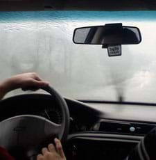 Photo shows rain on windshield, obscuring the view of the road ahead.