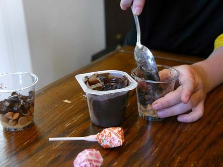 Childs hand spooning pudding into the cup.