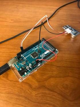 The image shows a breadboard with a USB cord connected to it.  Connected to the digital pins of the breadboard are the echo and trigger wires that connect to an ultrasound distance sensor.  The power and ground wires are connected on the opposite side near the analog pins.