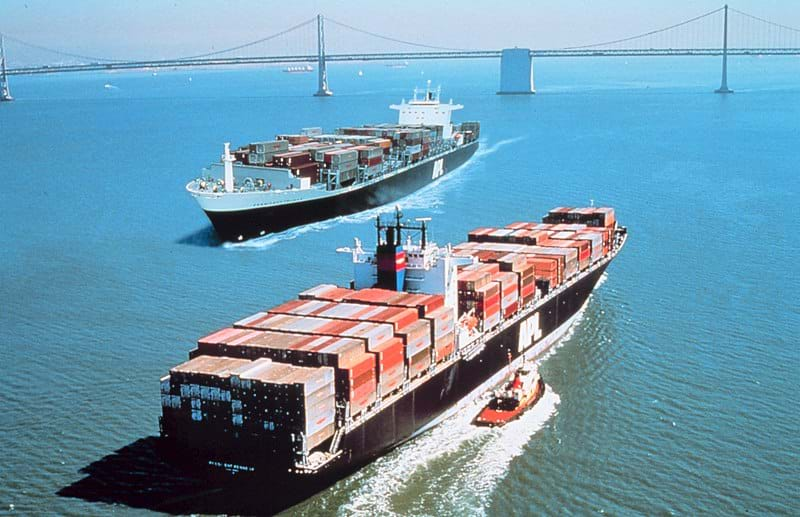 Two container ships pass by each other in a harbor.