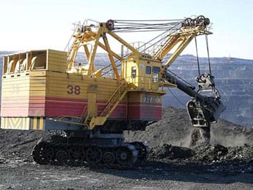 A photograph shows heavy equipment—an excavator—mining dark soil with its digger attachment. 