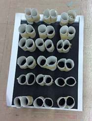 A photograph shows a student-engineered structural protein model composed of rolled up paper tubes taped into pairs and oriented vertically on a black sheet.