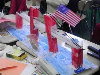 Photo shows a four-column, straight-span bridge that is colored red and blue (water), with a small American flag at the top of one of the middle pillars.