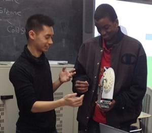 A photograph of two students holding the LEGO NXT rotary encoder that is constructed during this activity.