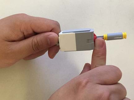Photo shows the hands of two students interacting with the touch sensor haptic attachments that they created.