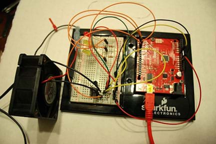 A photograph shows a completed homeostasis circuit composed of a breadboard, computer cooling fan, Arduino circuit board (SparkFun’s Redboard), jumper wires, resistors and other components.