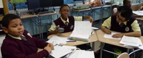 A photograph shows three students at a shared desk working with a LEGO-based light meter, showing their completed data line plot.