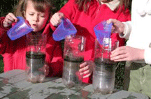 Photo shows three students conducting a basic permeability test using soda bottles, funnels, sample soils, and collection jars.