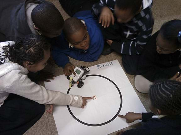 Six youngsters sit on the floor workingn on the Pi activity.