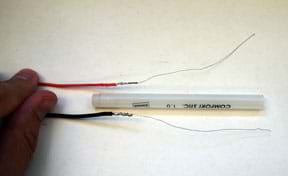 A photograph shows the two soldered wires laid parallel to each other with a long, cylindrical plastic piece between them, with the solder joints positioned near the end of the plastic piece.
