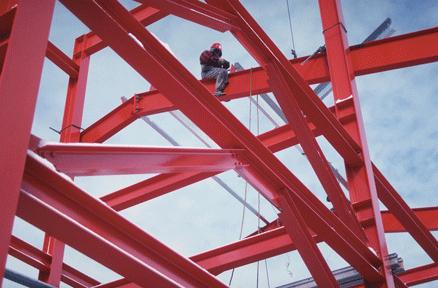 Photo shows a network of red steel beams under construction.