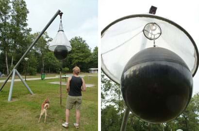 Two images show a metal tripod supporting an angular pole from which hangs about 4 meters from the ground a large, white cone (pointed side up) around a large black ball that hangs partially below the cone.