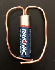 A piece of 14-gauge copper wire is bent to orient itself from the positive end of a Rayovac battery to the negative end.  This photo shows a front-facing view. 