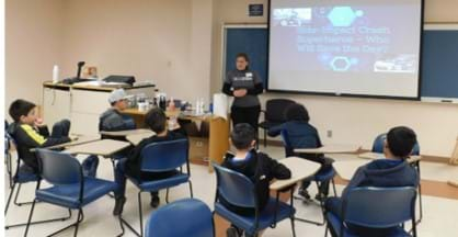 Teacher presenting a power point in front of students at their desks.