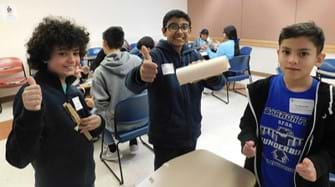 Students showing their final aluminum can car with safety feature product.