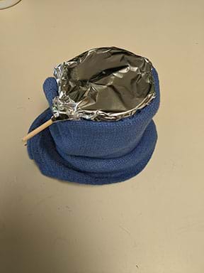 A photograph shows a beaker and skewer setup wrapped in a towel and covered with aluminum foil.