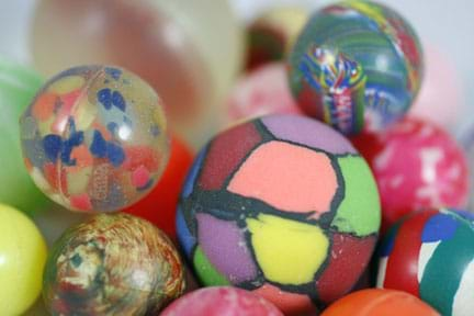 A photograph showing thirteen bouncy balls all consisting of different colors and sizes.