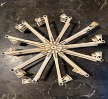 An assembled small wooden model Ferris wheel sits on its side on a table. 