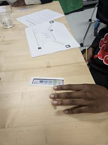 A photo showing a student using a glucose testing strip to test liquids and compare the resulting color.