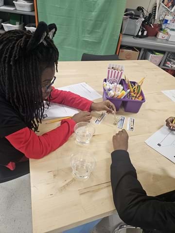 A photo showing a student holding a glucose testing strip next to a color chart.