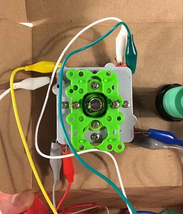 A close-up photograph shows the underside of the joystick that is mounted to the shoebox, now with numerous alligator clips attached to it.